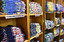 Shelves filled with neatly folded, colorful patterned shirts, each section labeled with different names.